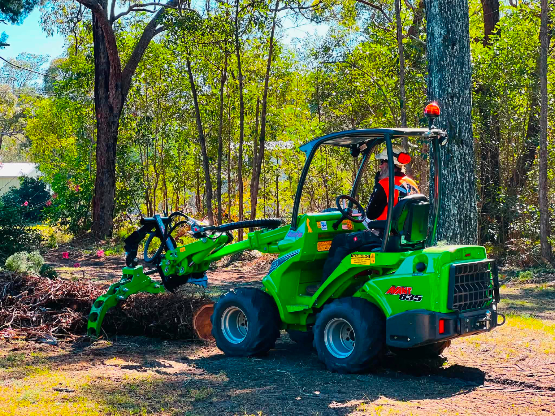 Loader with grapple saw moving cut timber